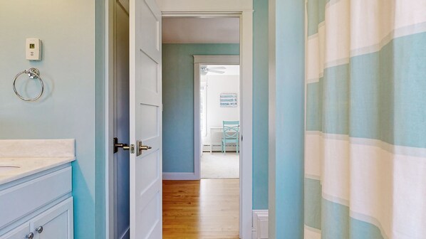 A hallway with a wooden floor, a white door, and a striped curtain.