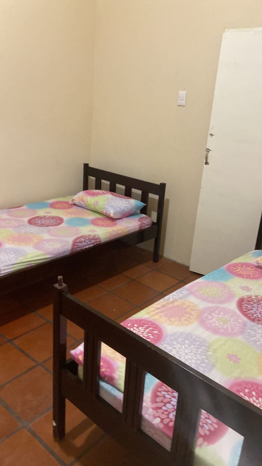Un alojamiento pequeño y de una sola habitación con dos camas individuales, cada una con una colcha estampada de flores.