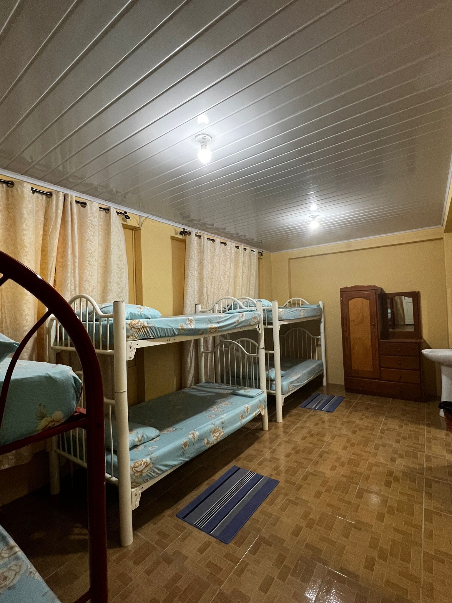 A room with bunk beds, a wooden wardrobe, and a sink.