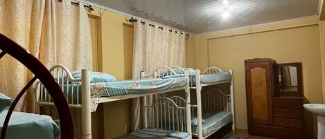 A room with bunk beds, a wooden wardrobe, and a sink.