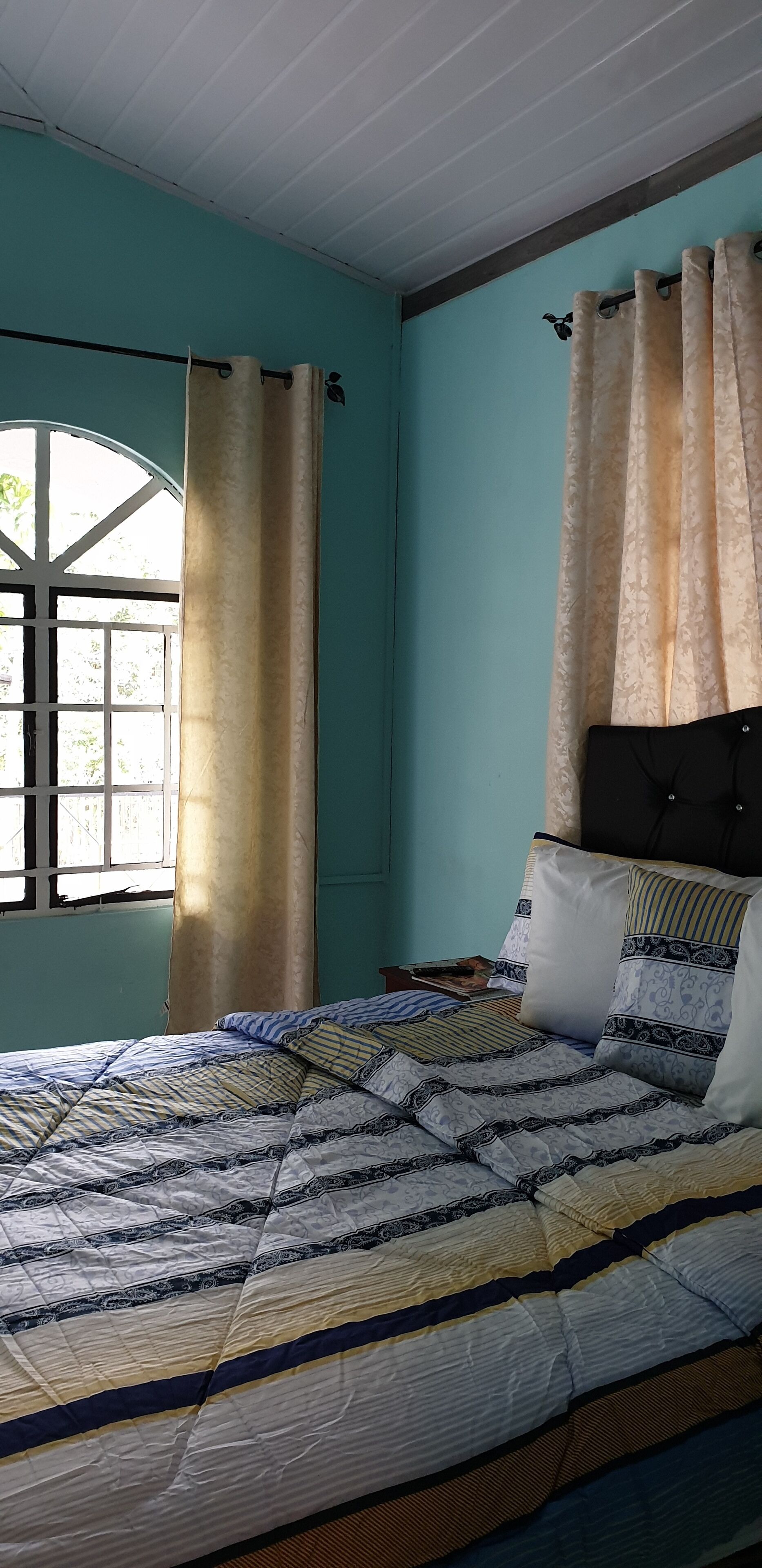 Un dormitorio con cama, cortinas y ventana.
