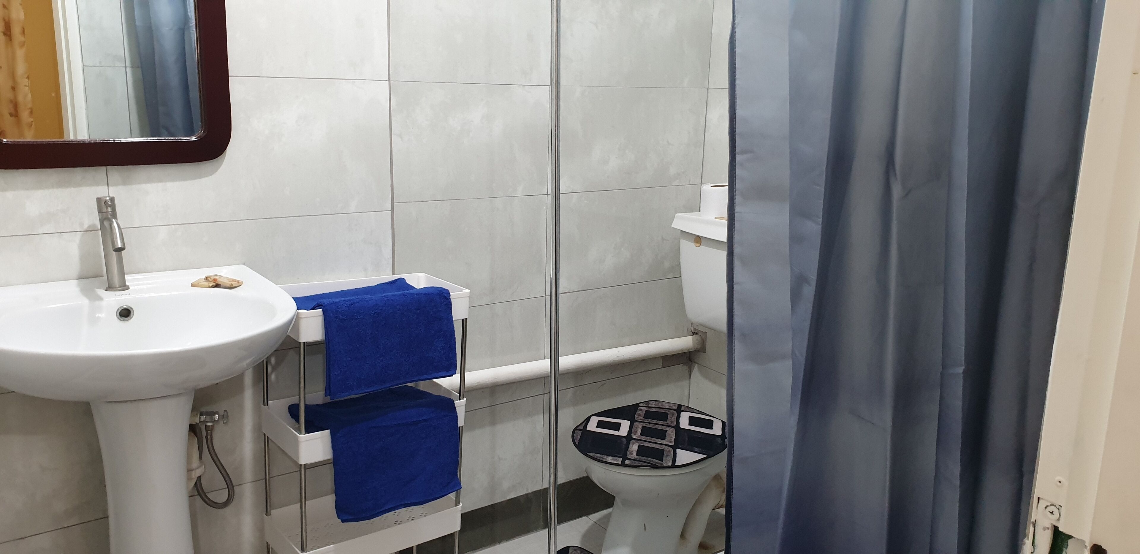 Une salle de bain avec un lavabo blanc, un miroir, des toilettes et un rideau de douche.