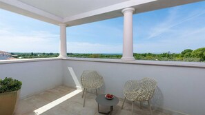 Enjoy the serene view from this balcony with a table and chairs, perfect for taking in the surroundings.