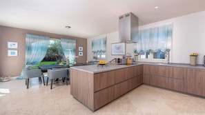 Enjoy cooking in this well-equipped kitchen with a large island, sink, and range hood, and dine in the adjacent seating area with a view of the garden.