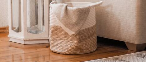 A cozy living room with a stone wall, a white sofa, a woven basket, and a white lantern.