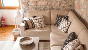 Una sala de estar con pared de piedra, un sofá, una mesa de centro y una lámpara colgante.