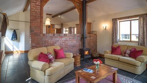 A cozy living room with two sofas, a fireplace, and a large mirror reflecting the room. - Beili Stable, a spacious country barn near Monmouth with spectacular views (The Hendre)