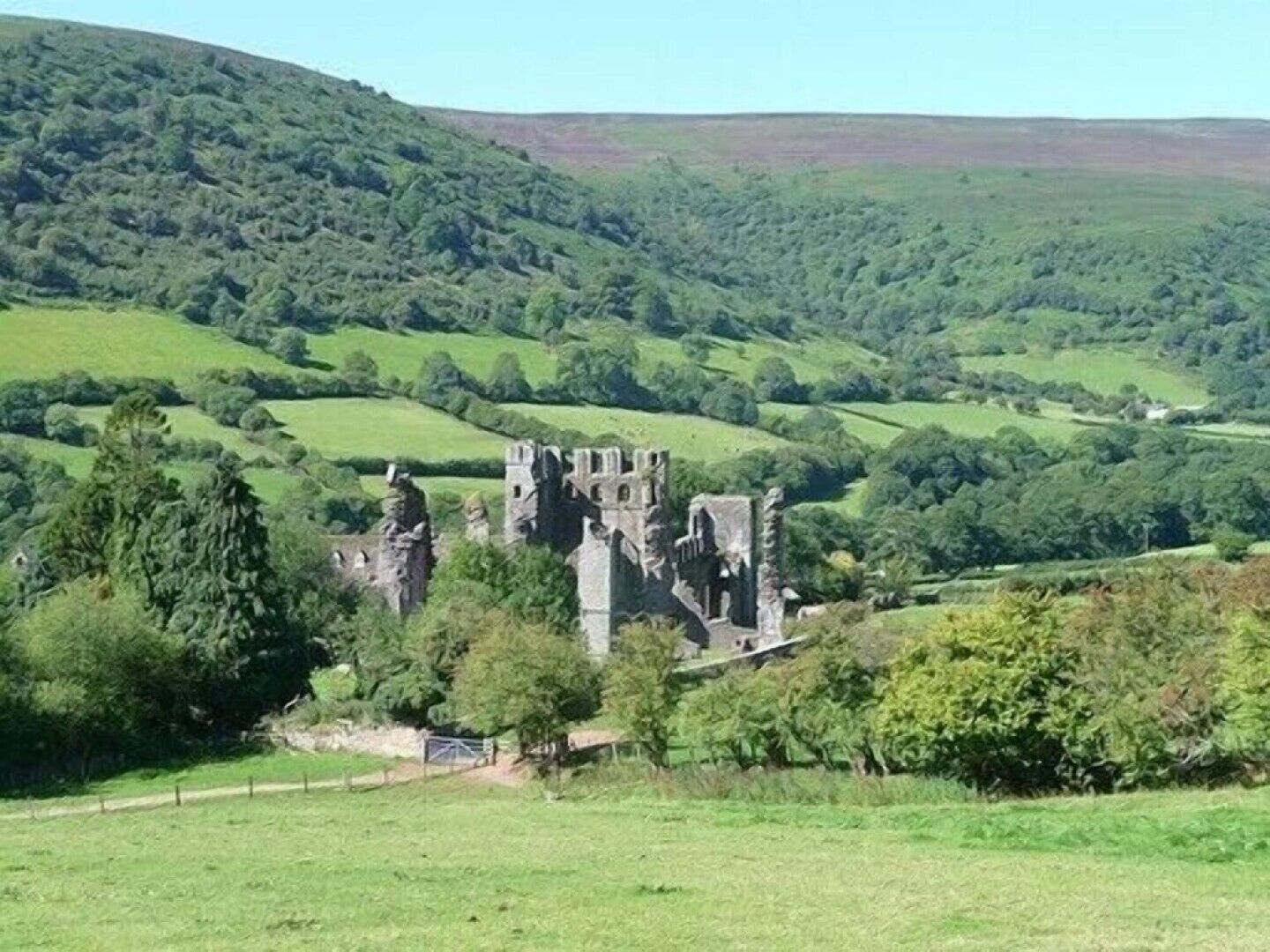 A historic stone castle surrounded by lush green hills and fields.