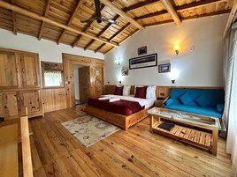 Una habitación con suelo de madera, una cama, un sofá y una mesa de centro de vidrio.
