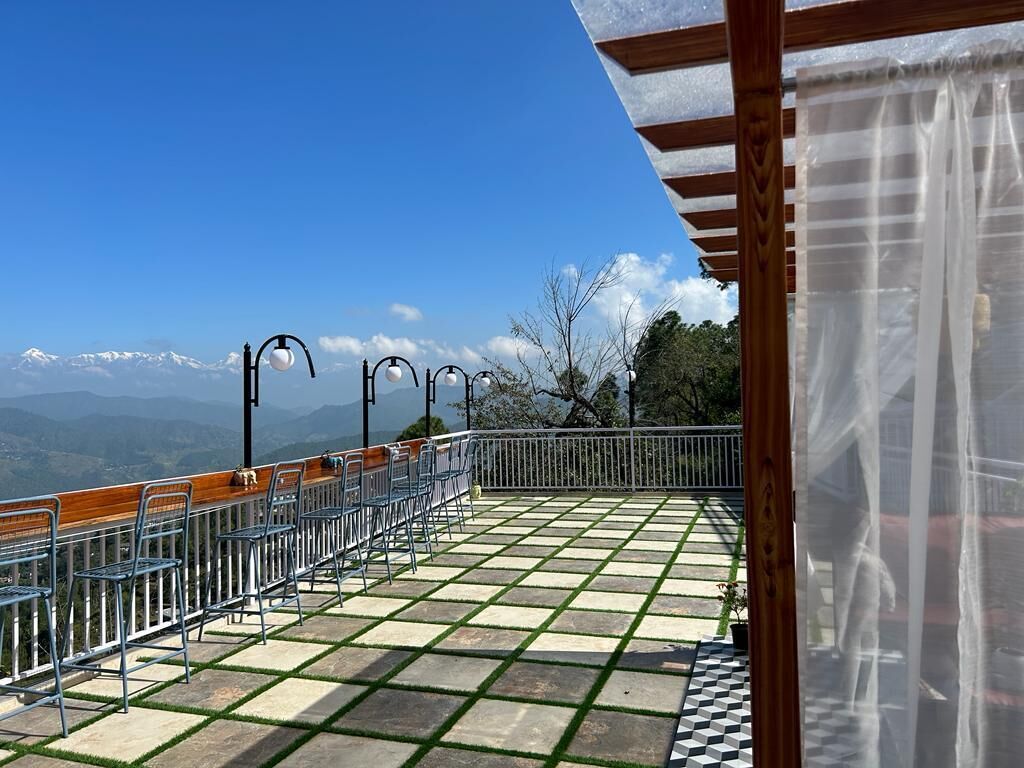 A terrace with a view of mountains, metal chairs, and a pergola.