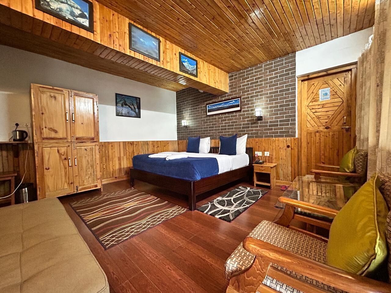 Habitación con detalles de madera, una cama, un sofá y un televisor montado en la pared.