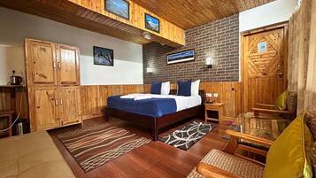 Habitación con detalles de madera, una cama, un sofá y un televisor montado en la pared.