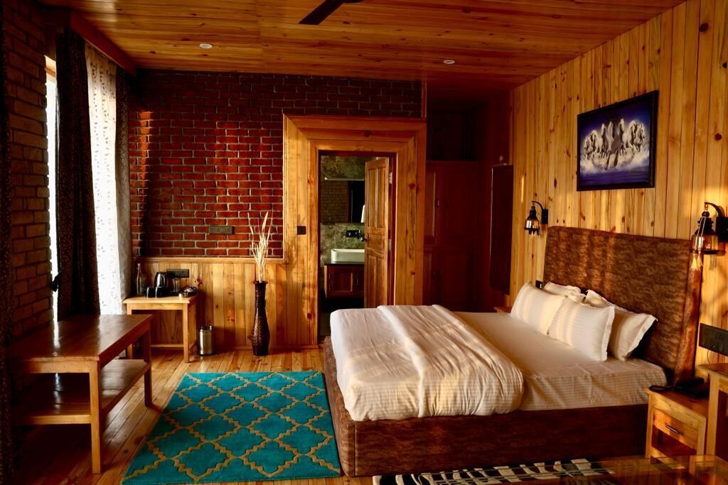 Una habitación con paneles de madera, una cama, un escritorio y una pequeña mesa.