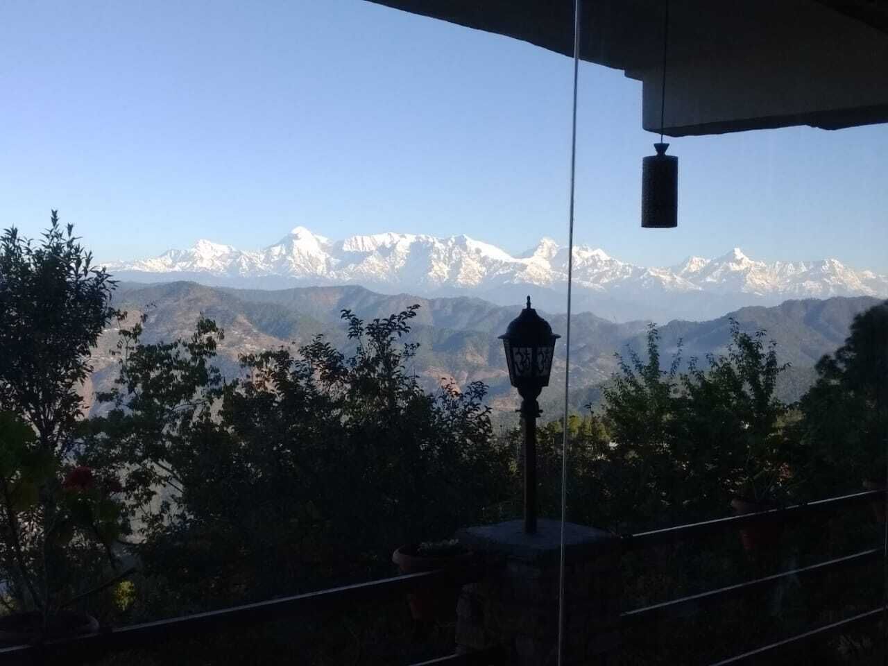 A mountain view with snow-capped peaks, a street lamp, and trees in the foreground.