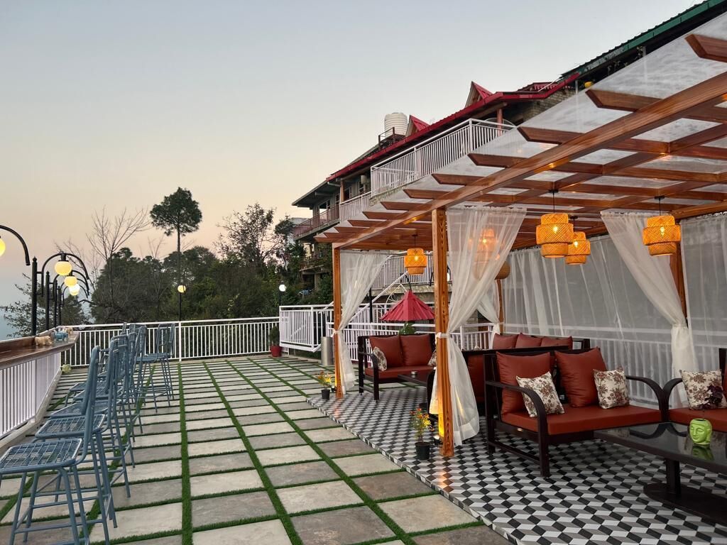 Una terraza con suelo a cuadros, mobiliario exterior y una zona cubierta con vistas al cielo.