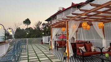 Una terraza con suelo a cuadros, mobiliario exterior y una zona cubierta con vistas al cielo.