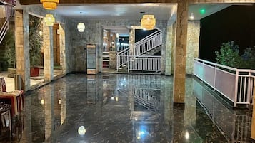 Eine großzügige Lobby mit poliertem Marmorboden, einer Treppe und hängenden Pendelleuchten.