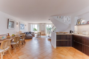 Un amplio espacio de estar con mesa de comedor, sillas, sofá y una cocina con armarios y encimera.