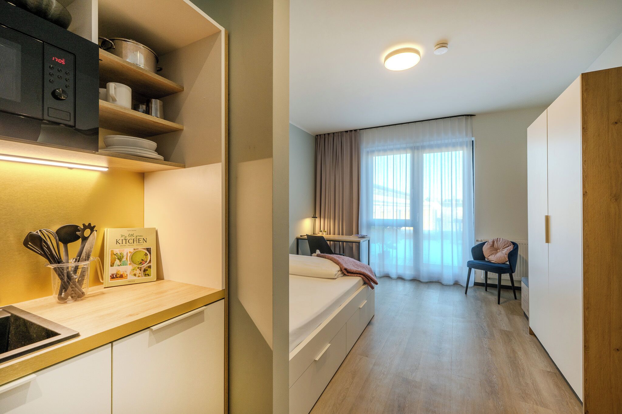 A hotel room with a kitchenette, a bed, a desk, and a chair.
