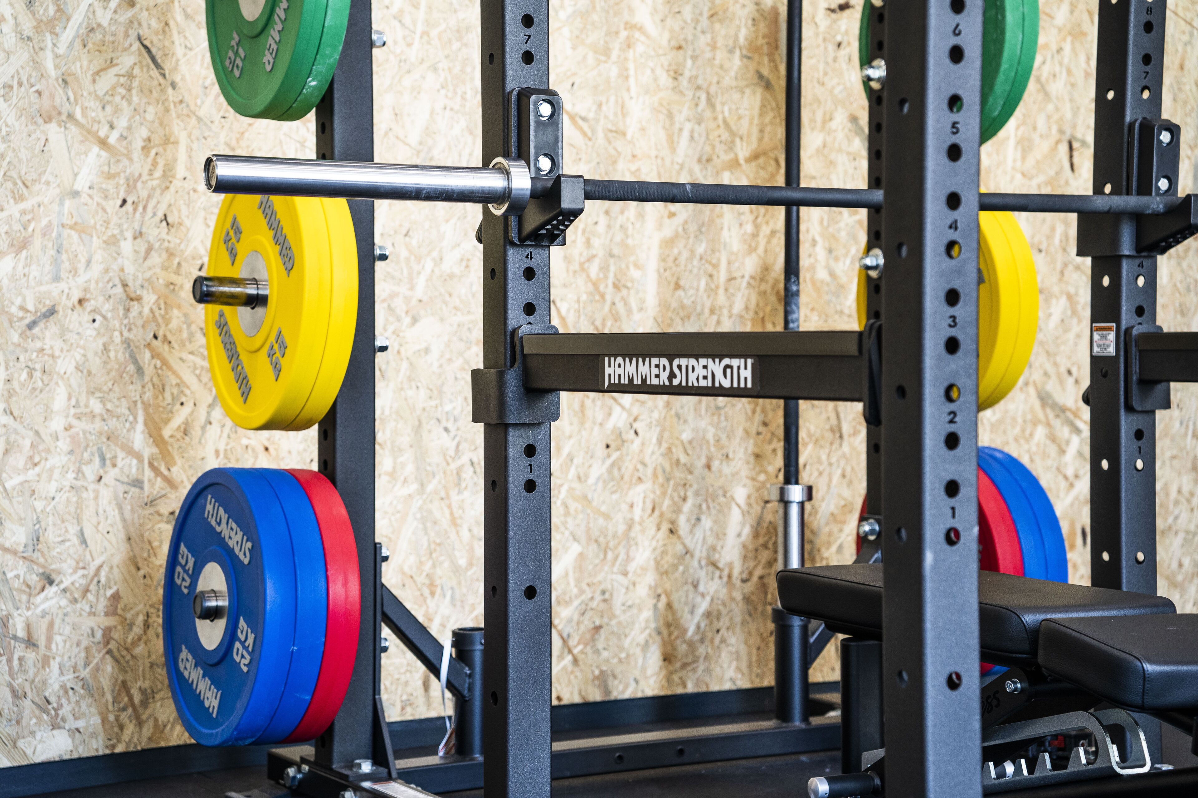A weightlifting rack with various weight plates and a bench.