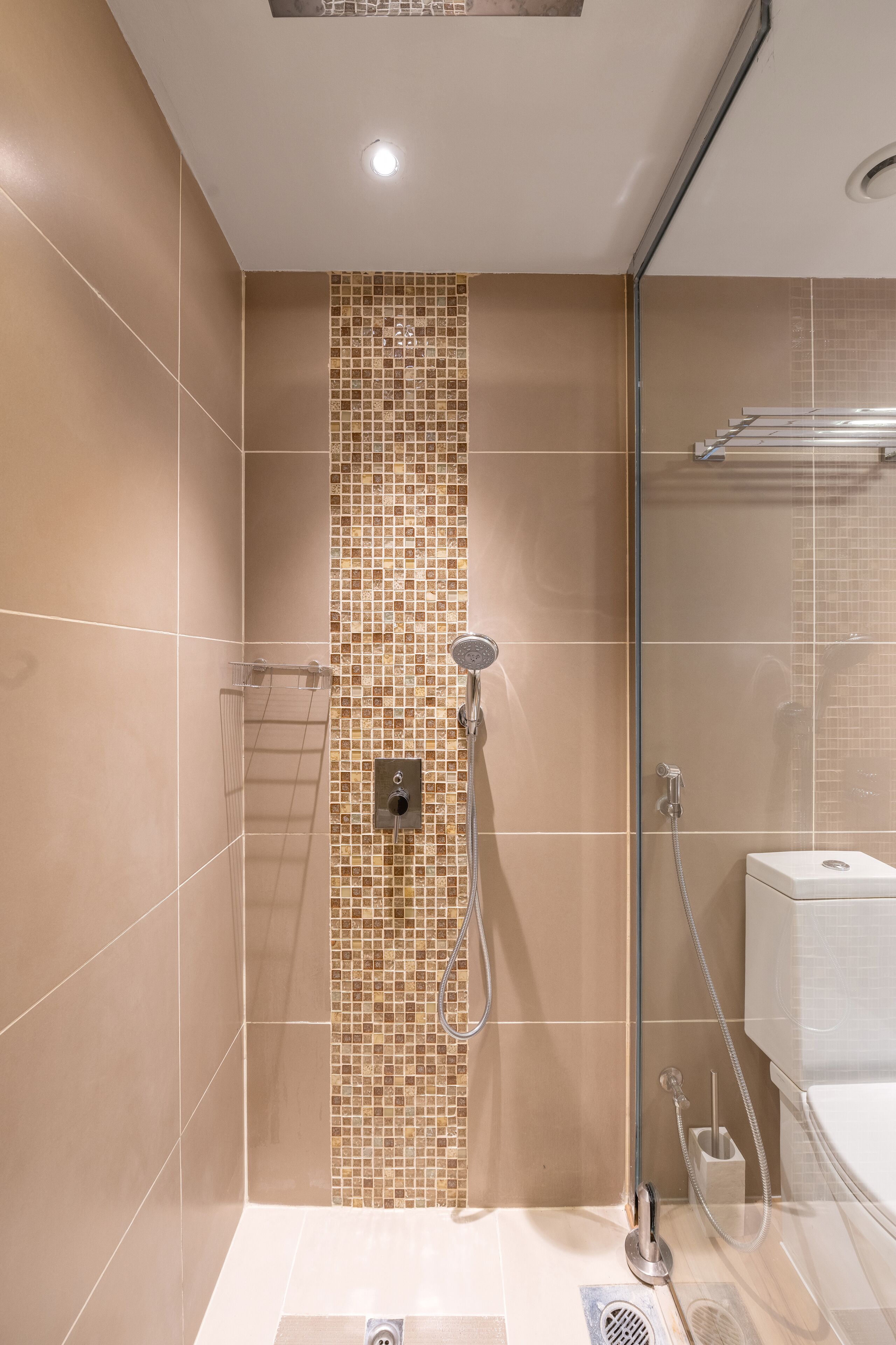 A modern bathroom with a shower, tiled walls, and a glass door.