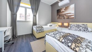 Ein Hotelzimmer mit zwei Betten, einem Schreibtisch und einem Fenster mit Vorhängen.