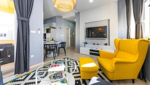 Ein modernes Wohnzimmer mit einem gelben Sessel, einem runden Couchtisch und einem an der Wand befestigten Fernseher.
