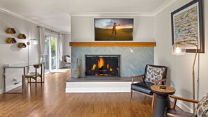 A living room with a fireplace, a large painting, and a modern chair.