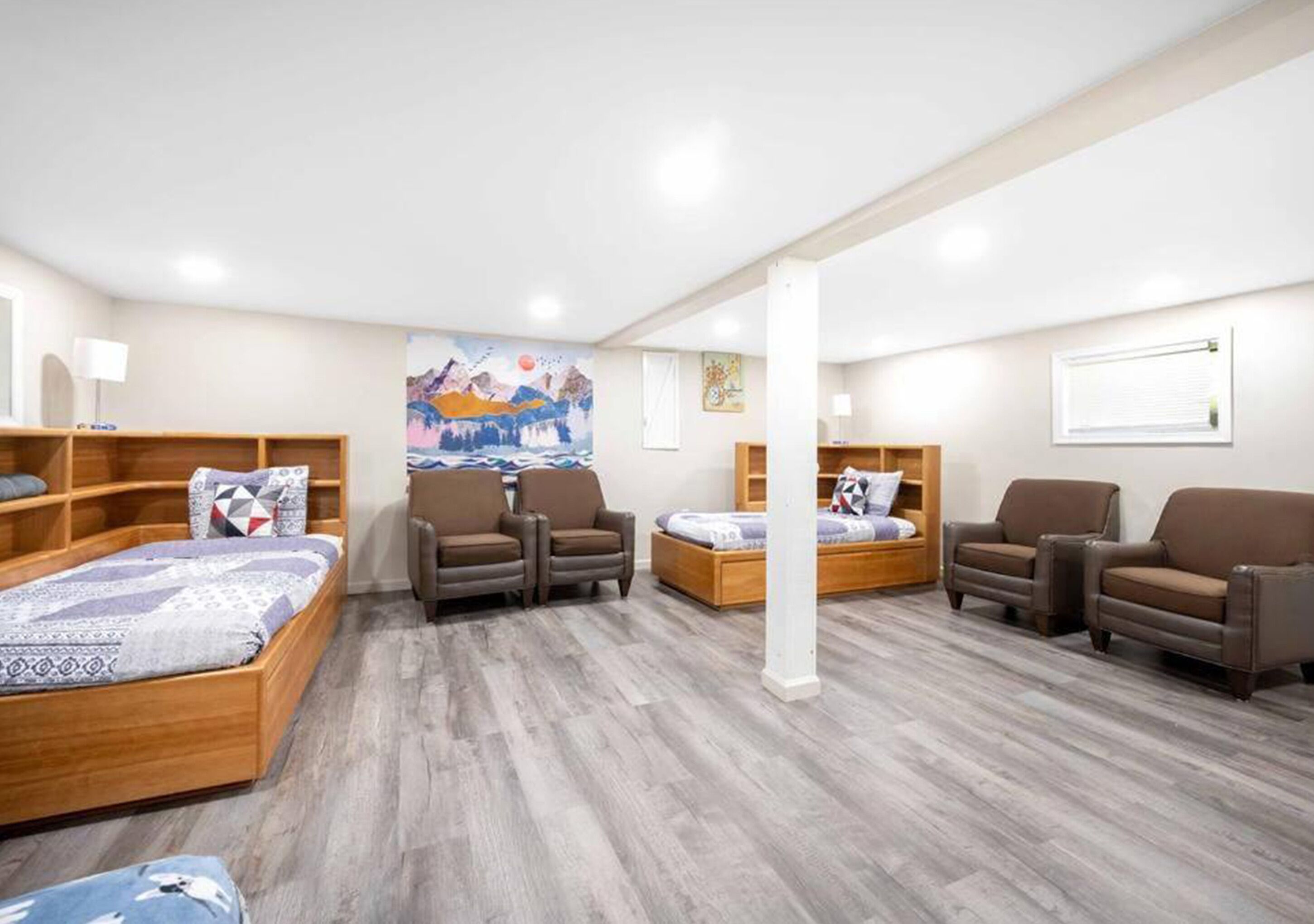 A hotel room with a wooden bed, two armchairs, a sofa, and a wooden cabinet.