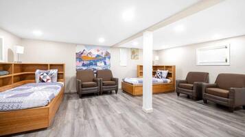 A hotel room with a wooden bed, two armchairs, a sofa, and a wooden cabinet.