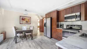 A modern kitchen with wooden cabinets, stainless steel appliances, and a marble countertop. - Garden View Home (Tobyhanna)