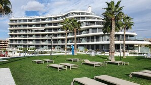 Un hôtel à plusieurs étages doté d’une terrasse et de palmiers.