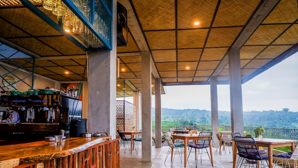 An outdoor seating area with tables and chairs, a bar with a counter, and a view of the landscape. - Gunza Bed and Breakfast (Penebel)
