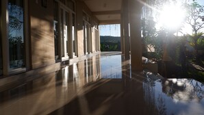 A spacious corridor with reflective flooring, large windows, and a view of greenery outside. - Gunza Bed and Breakfast (Penebel)