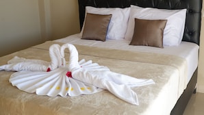 A neatly made bed with a swan towel and two pillows. - Gunza Bed and Breakfast (Penebel)