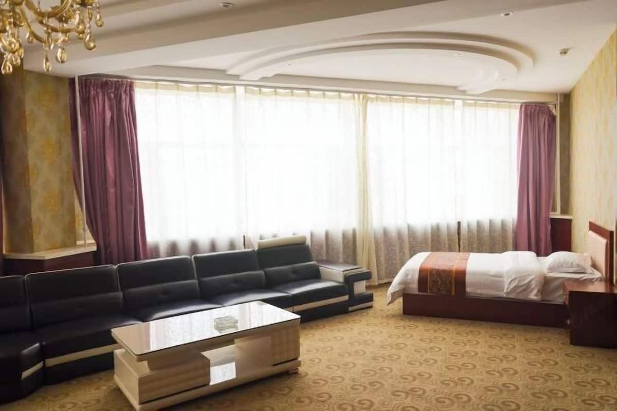 Ein Hotelzimmer mit einer Couch, einem Bett, einem Couchtisch und einem Kronleuchter.