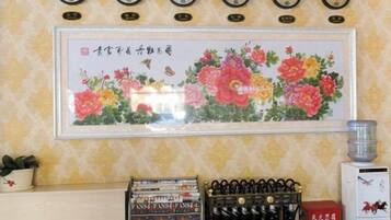 A wall with clocks, a framed floral painting, and a water dispenser.