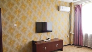 A room with a patterned wallpaper, a flat-screen TV mounted on the wall, a wooden cabinet, and a window with curtains. - Lidu International Hotel (Ar Horqin Banner)
