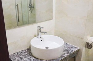 Un baño con un lavamanos blanco, un espejo y una ducha.