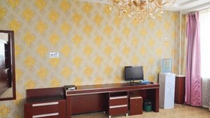 Een hotelkamer met een bureau, televisie en een minibar.