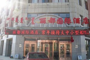 A hotel entrance with a signboard, glass doors, and a red car parked outside. - Lidu International Hotel (Ar Horqin Banner)