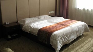 Een hotelkamer met een groot bed, een nachtkastje en een raam met gordijnen.
