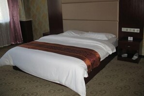 Une chambre d’hôtel équipée d’un lit, d’une table de chevet et d’un panneau de commande fixé au mur.