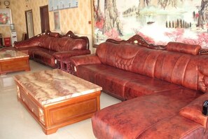 A living room with leather sofas and a wooden coffee table. - Lidu International Hotel (Ar Horqin Banner)