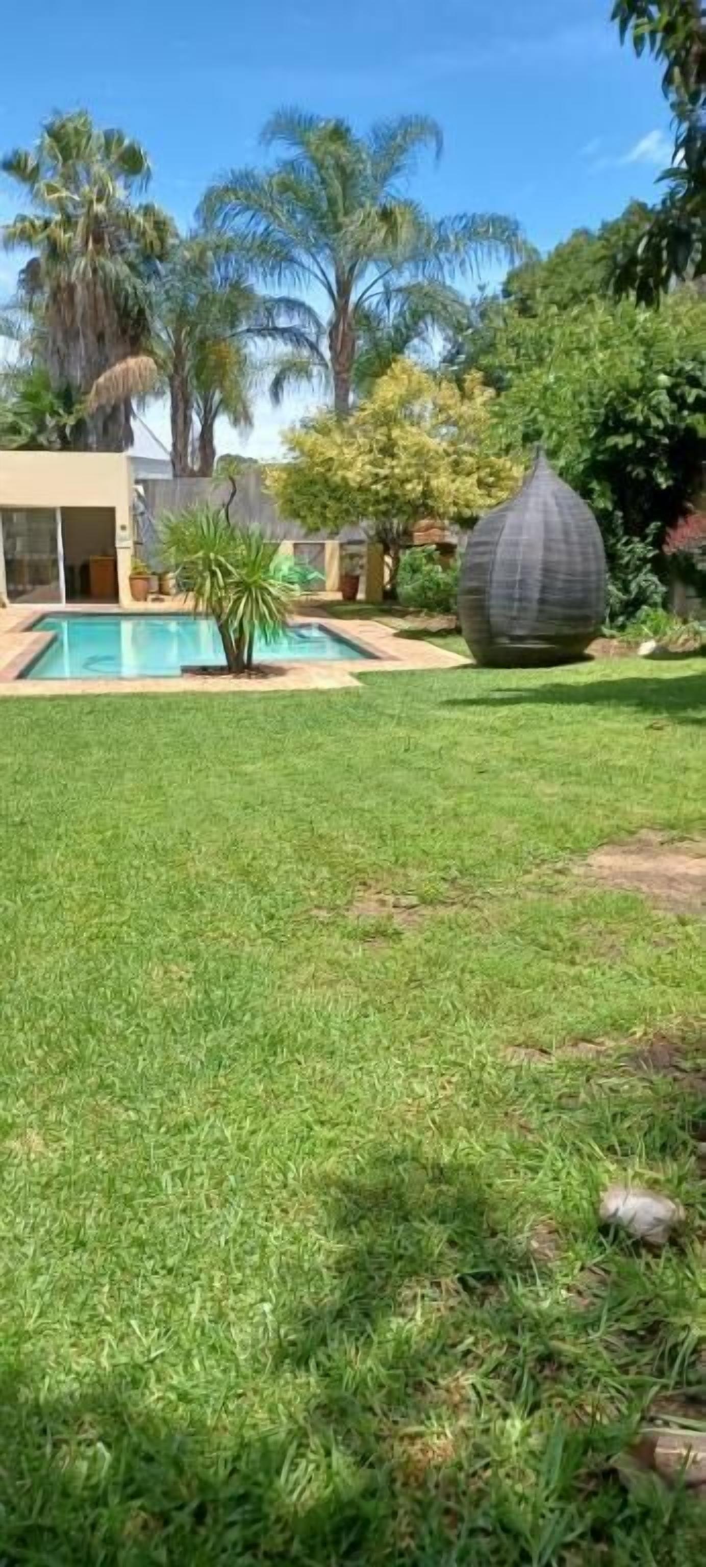 Un césped cuidado con piscina y una gran escultura decorativa.
