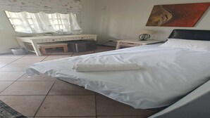 Un dormitori amb un llit, escriptori, cadira, làmpada i un quadre a la paret.