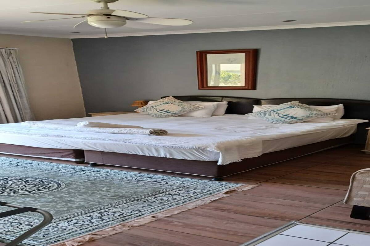 Ein Schlafzimmer mit einem großen Bett, einem Deckenventilator, Holzboden und einem gemusterten Teppich.