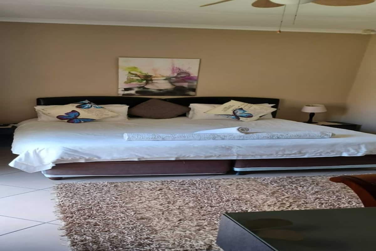 Ein Schlafzimmer mit Bett, Kissen, einem Nachttisch, einer Lampe und einem Bild an der Wand.
