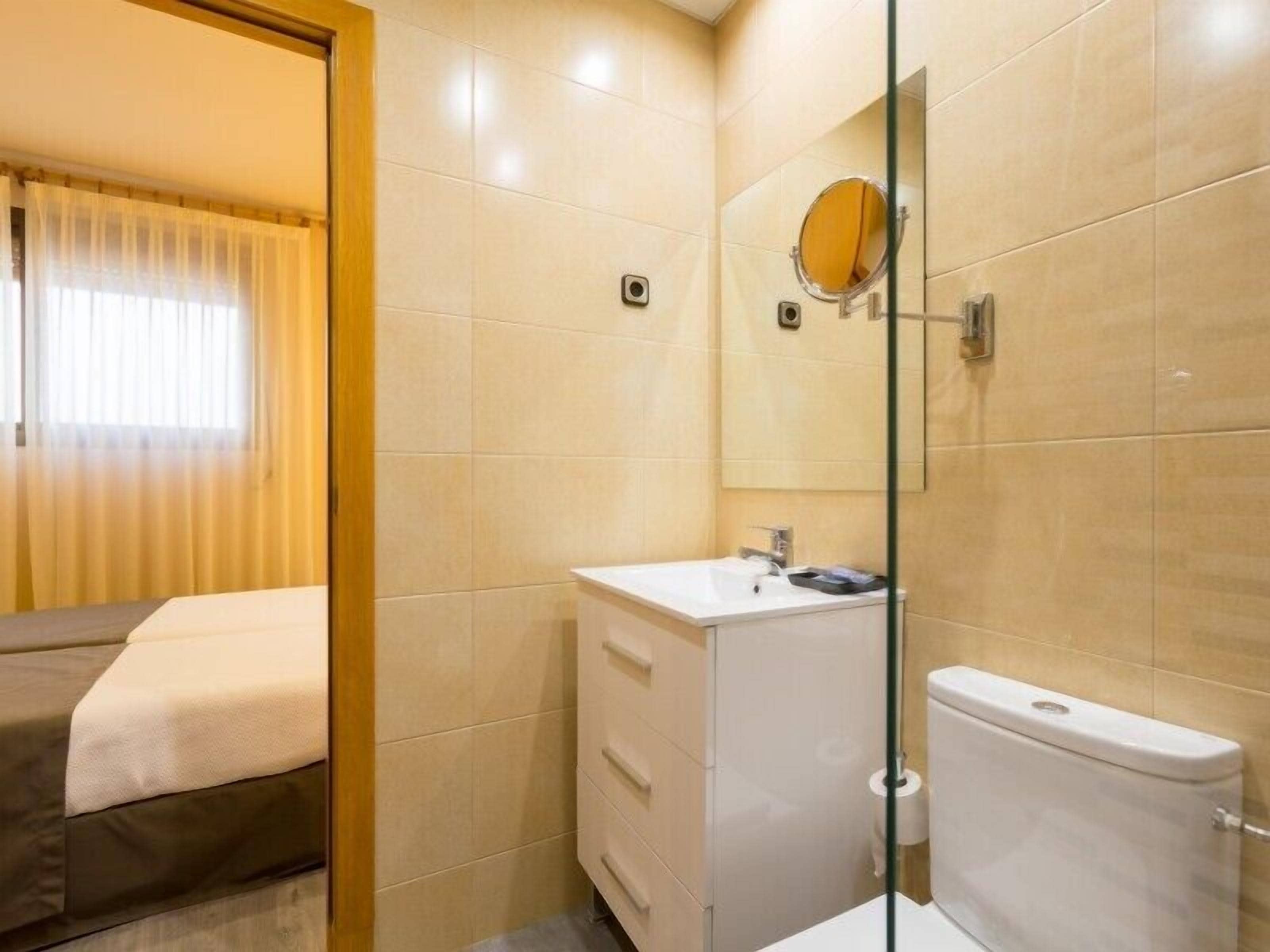 Un baño de hotel con inodoro, lavabo y espejo.