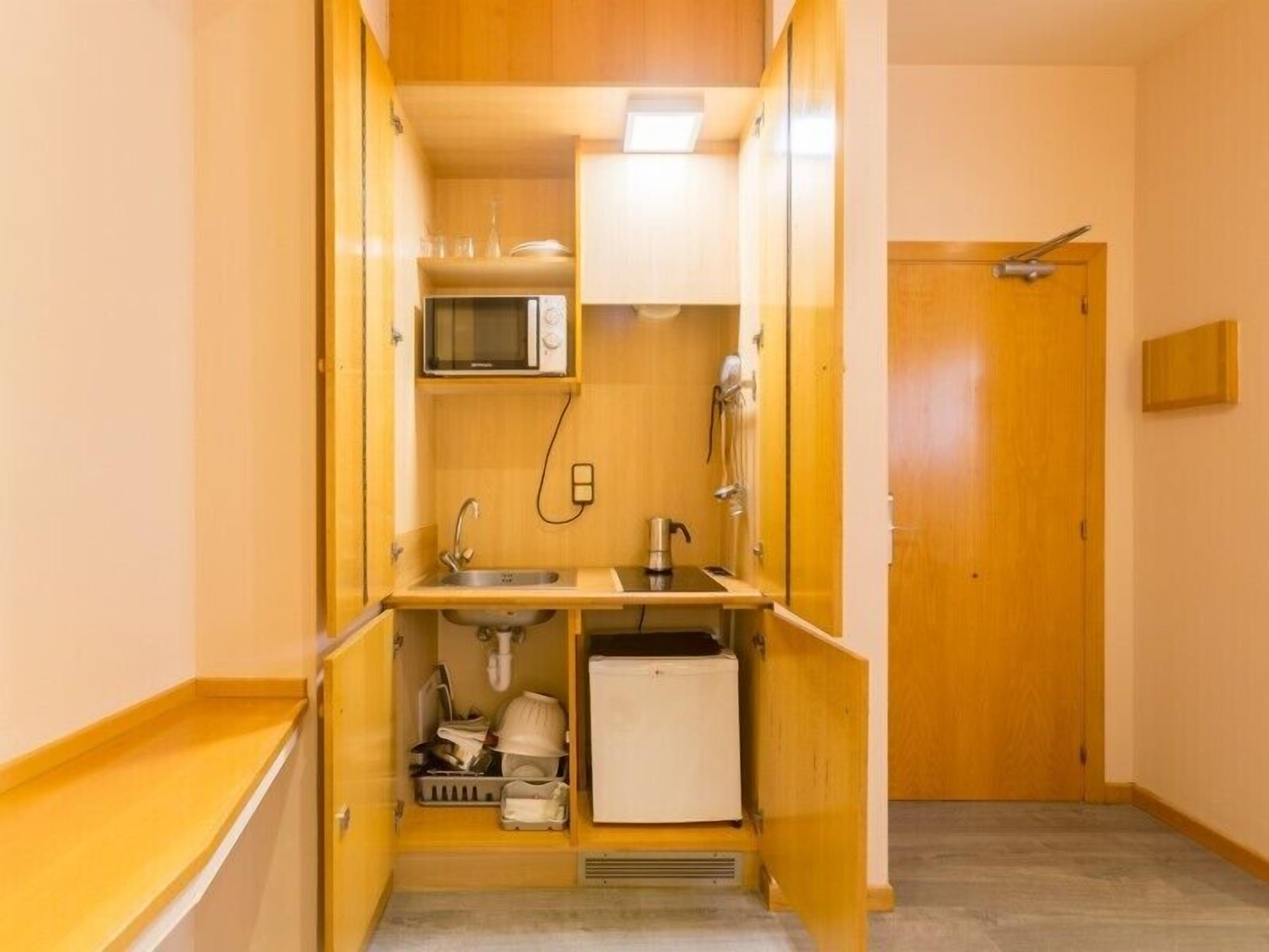 A compact kitchen with a microwave, sink, and small refrigerator.